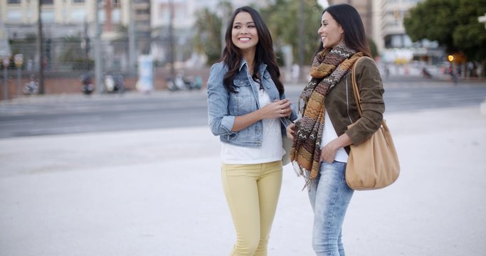 Two stylish women chatting outdoors in a town