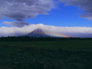 Fototapeta premium После бури. Буря почти кончилась, ветер еще дует, а рядом с вулканом возникла радуга.