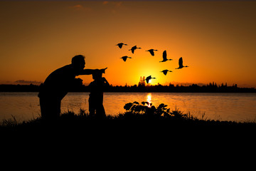 Fototapeta na wymiar silhouette father and son play binoculars sunset background