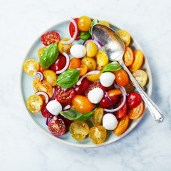 Fresh tomatoes with basil leaves in a bowl
