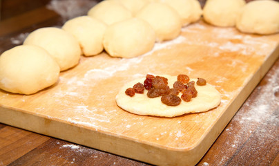 The cut dough for pies and one flat cake strewed with raisin on