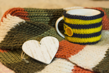 Wooden empty heart inscription on the background of cups in a knitted cover