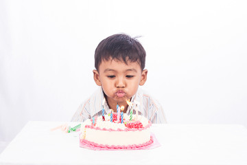 little asian boy blowing birthday cake