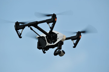 white drone hovering in a bright blue sky