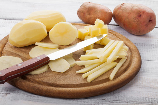 Raw peeled and sliced potatoes on cutting board