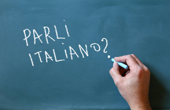 male hand writing over chalkboard do you speak italian
