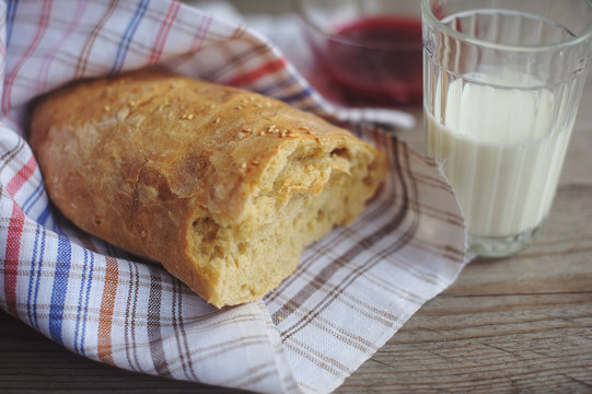 Freshly baked bread served with jam and glass of milk.