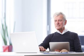 Senior businessman with laptop and digital tablet