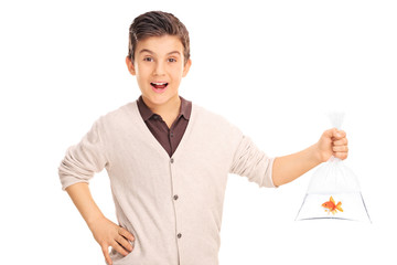 Cheerful boy holding a goldfish in a plastic bag