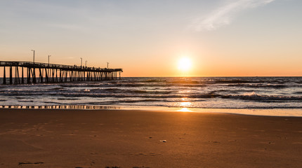 Virginia Beach, Virginia boardwalk fishing pier with the sun at the horizon.