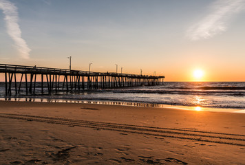 Virginia Beach, Virginia boardwalk fishing pier and beach at dawn. 