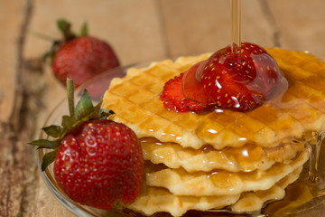 pouring syrup on waffles with strawberry
