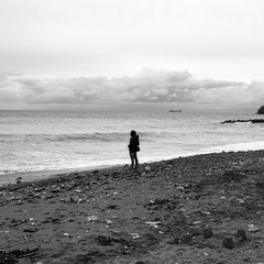 Girl standing in front of the sea. Black and white photo