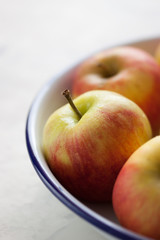 Red yellow apple in an enamel plate with blue edge, closeup, selective focus