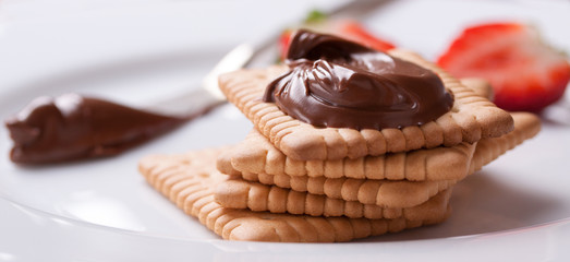 Chocolate sweet melting nougat cream on cookies with strawberries on a white plate, horizontal,  closeup