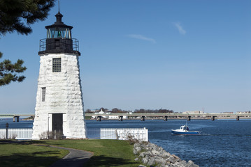 Newport Harbor lighthouse guiding lobster boat in Rhode Island on a sunny day.