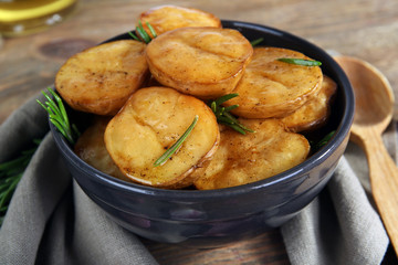 Delicious baked potato with rosemary in bowl on table close up