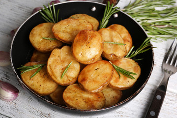 Delicious baked potato with rosemary in frying pan on table close up