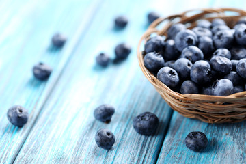 Tasty blueberries in basket on a blue wooden table