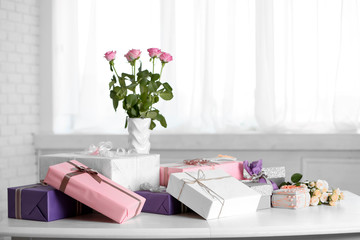 Composition of cute gift boxes and roses on white table