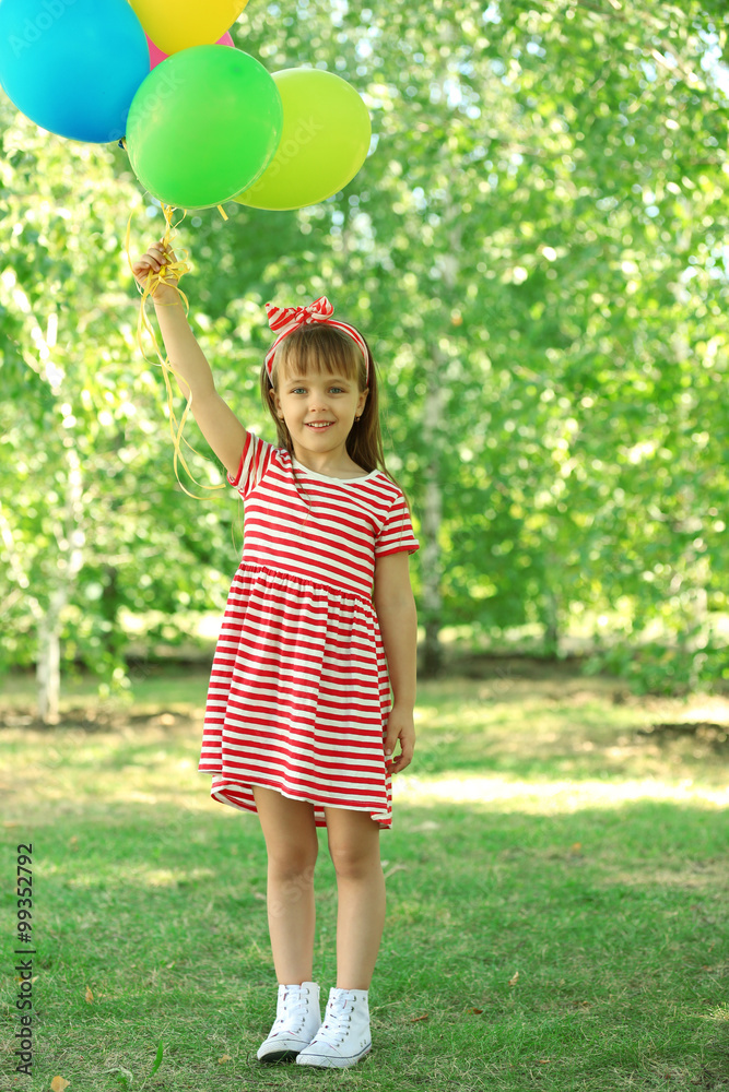 Wall mural Little girl playing with balloons in the park