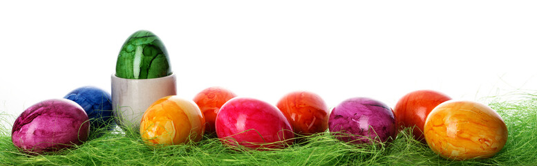 Bunt gefärbte Ostereier in grünem Grasnest vor hellem Hintergrund