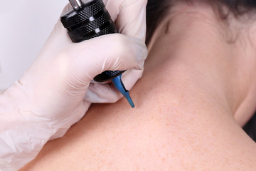 Tattooist draws on the woman's neck on white background, close up