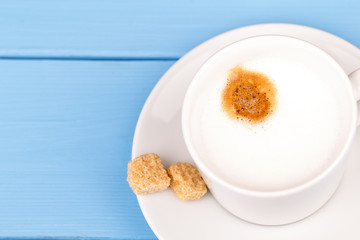 Cappuccino and cane sugar on a blue table