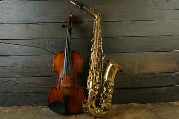 Beautiful golden saxophone with violin on wooden background