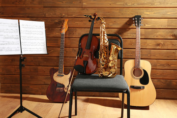 Musical instruments on a chair and note holder against wooden background