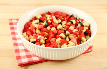 Ratatouille, stewed vegetable dish with tomatoes, zucchini, eggplant before cooking, on wooden background