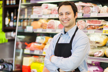 Smiling shopkeeper in a grocery store - obrazy, fototapety, plakaty