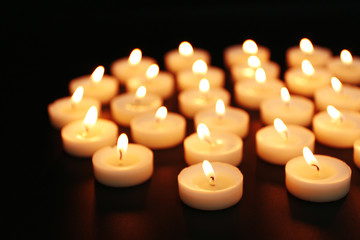 Alight candles in a row on black background