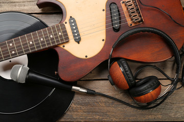 Naklejka premium Electric guitar and headphones with microphone and vinyl on wooden background