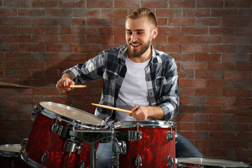 Musician playing the drums on brick wall background