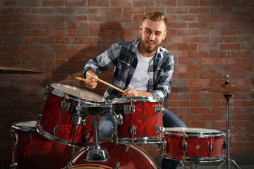 Musician playing the drums on brick wall background