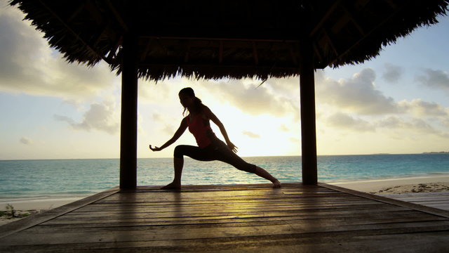 Sunrise silhouette of young girl practicing yoga