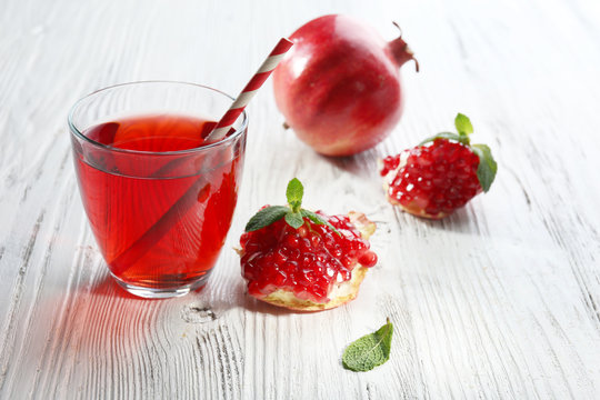 A glass of tasty juice and garnet fruit, on wooden background