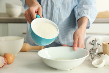 Woman is adding sugar to the egg mixture