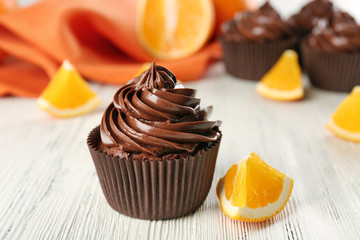 Chocolate cupcakes served with orange on table
