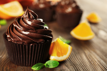 Chocolate cupcakes served with orange and mint on a table