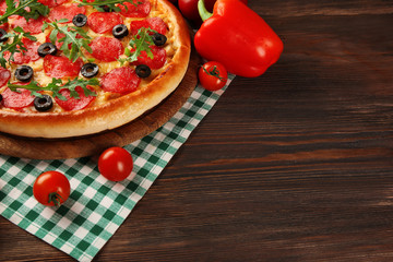 Tasty pizza with salami on decorated wooden table