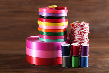 Spools of color ribbon and thread on wooden background