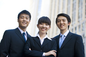 Three business professionals in front of skyscraper