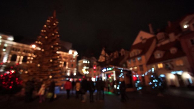 People visit Christmas Fair in old town at evening in Riga, Latvia. Blurred