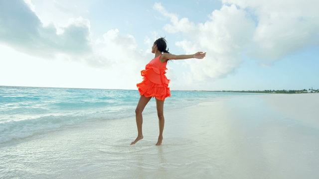 African American girl in red dress barefoot on ocean sand
