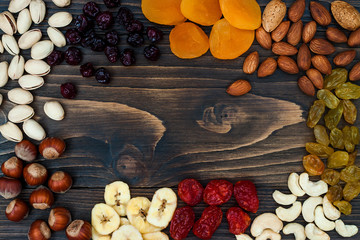 Mix of dried fruits and nuts on a dark wood background with copy space. Top view. Symbols of judaic holiday Tu Bishvat