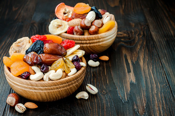 Mix of dried fruits and nuts on dark wood background with copy space. Symbols of judaic holiday Tu Bishvat