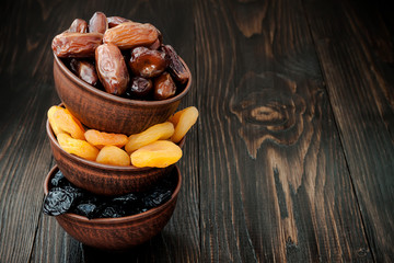 Mix of dried fruits and nuts on dark wood background with copy space. Symbols of judaic holiday Tu Bishvat