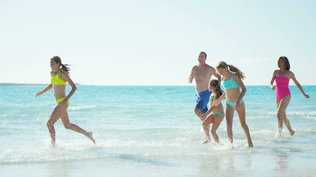 Young Caucasian family in swimwear having fun on beach